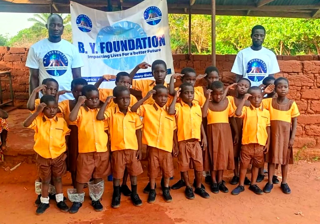 Schoolchildren in uniform with B.Y. Foundation volunteers