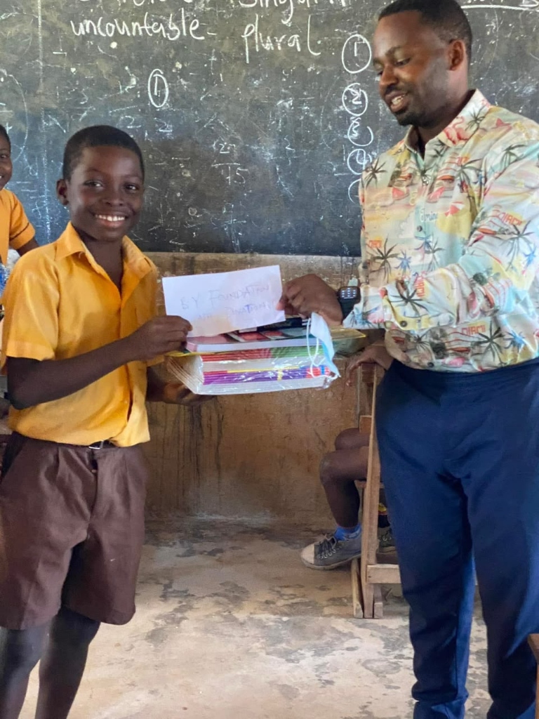 A child receiving school materials from the B.Y. Foundation